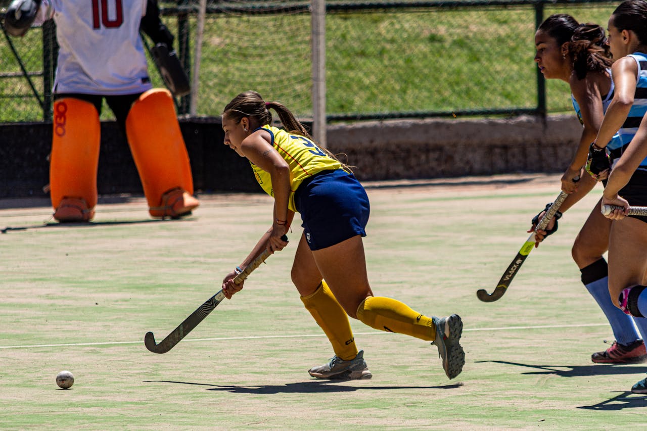 Dynamic field hockey match with players in active competition outdoors.